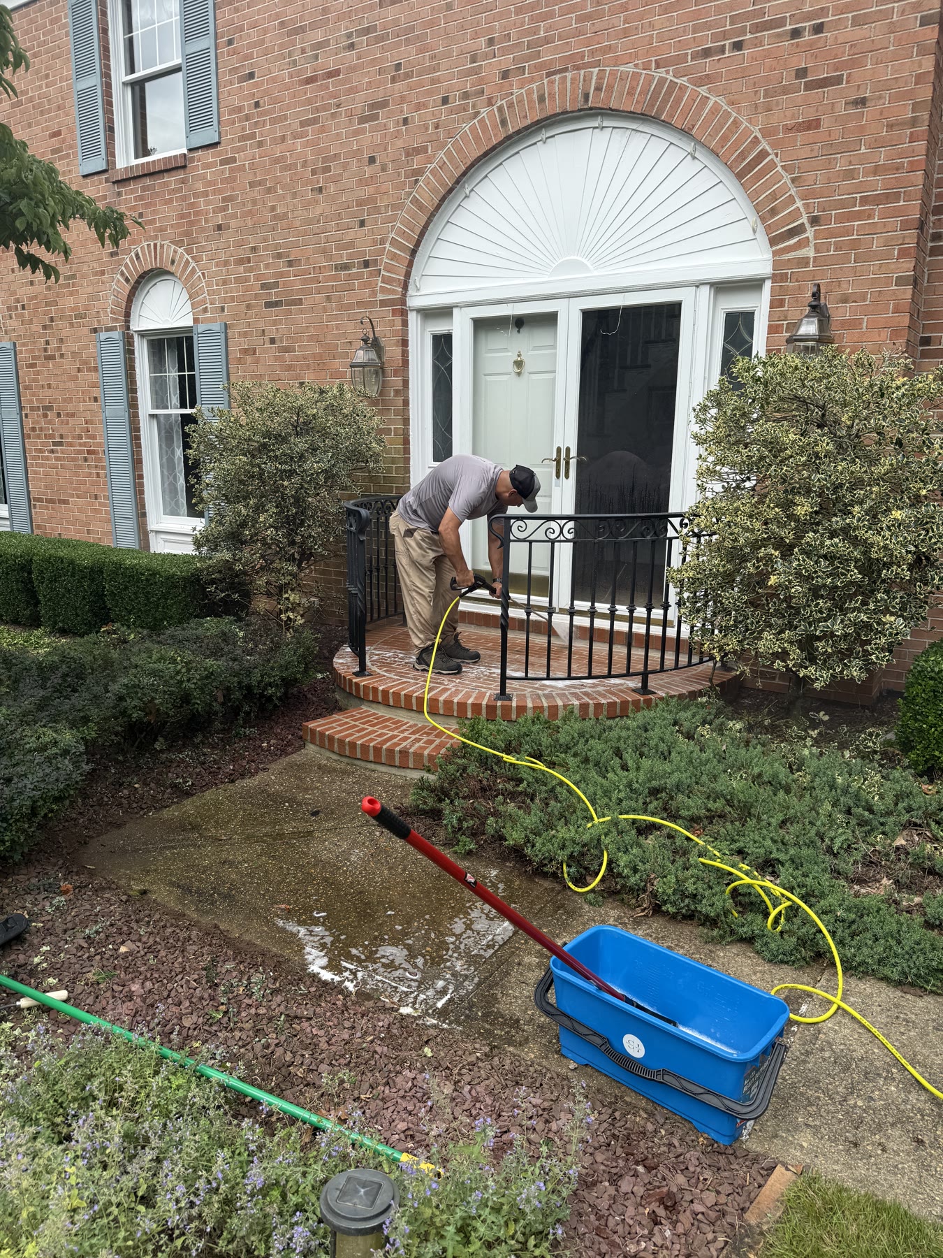 Technician power washing a brick front entry
